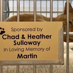 An animal cage with a plaque on it showing the sponsor